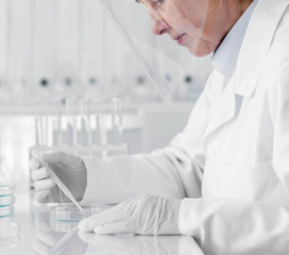 Un ricercatore o un tecnico di laboratorio sta eseguendo un'analisi scientifica utilizzando una pipetta e una piastra Petri in un ambiente di laboratorio pulito e sterile.